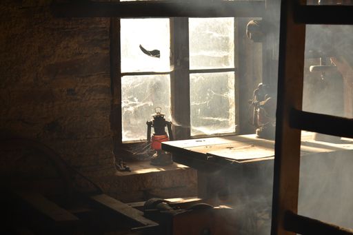 Some old dusty furniture in an abandoned house with light shining through the window