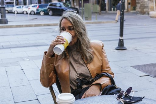 A shallow focus shot of a woman sitting in a cafeteria drinking coffee