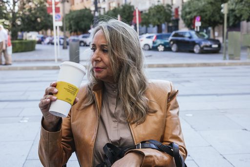 A shallow focus shot of a woman sitting in a cafeteria drinking coffee