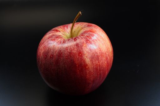 A closeup shot of a ripe apple on a black background in backlight