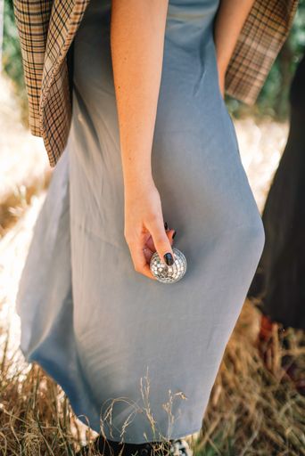 A vertical shot of a female hand holding a mirror disco ball