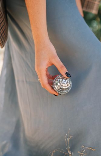 A vertical shot of a female hand holding a mirror disco ball