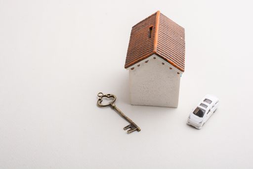 A closeup of a house coin bank next to a car and a key - concept of savings