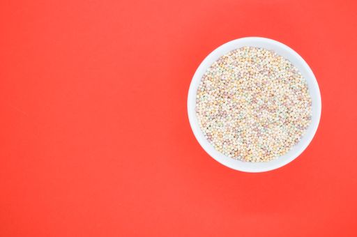 A high angle shot of a bowl of cornflakes on a red surface
