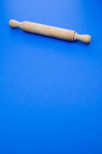 A vertical shot of a rolling pin on a blue surface