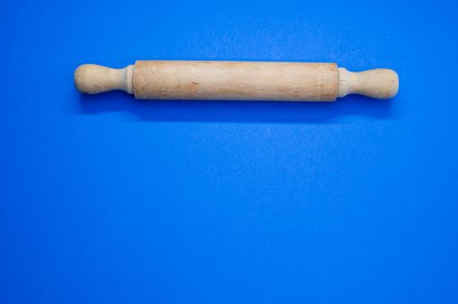 A high angle shot of a rolling pin on a blue surface