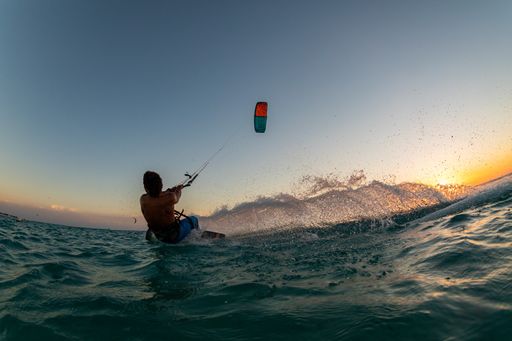 A person surfing and flying a parachute at the same time in Kitesurfing. Bonaire, Caribbean