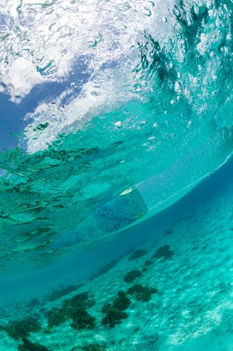 A vertical low angle shot of a person kitesurfing taken from the underwater in Bonaire, Caribbean