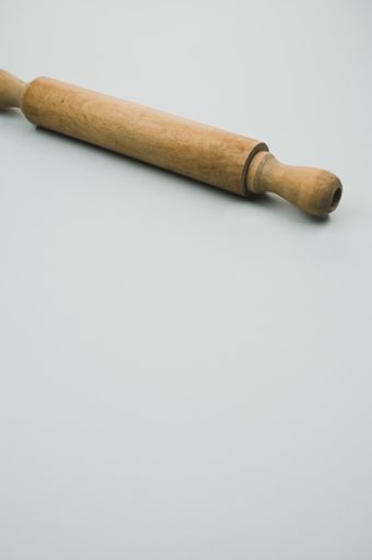 A vertical shot of a rolling pin on a blue surface