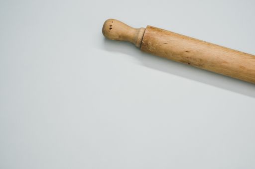 A high angle shot of a rolling pin on a blue surface
