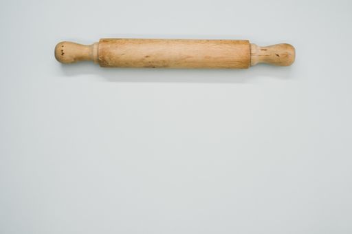 A high angle shot of a rolling pin on a blue surface