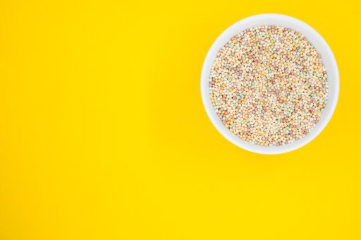 A high angle shot of a bowl of cornflakes on a yellow surface
