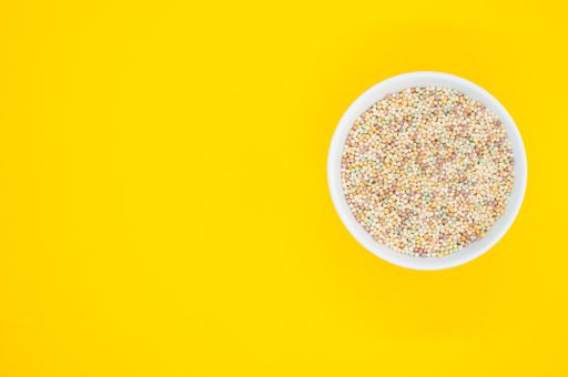 A high angle shot of a bowl of cornflakes on a yellow surface