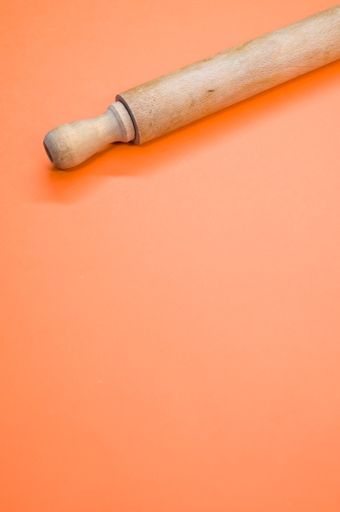 A vertical shot of a rolling pin on an orange surface