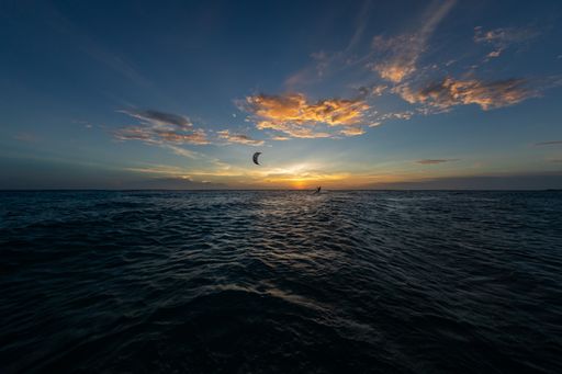 A person kitesurfing during the breathtaking sunset reflecting in the ocean in Bonaire, Caribbean