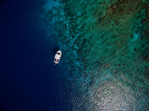An aerial shot of a boat on the beautiful blue ocean in Bonaire, Caribbean