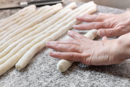 A closeup shot of making rolls for gnocchi on marble table with flour