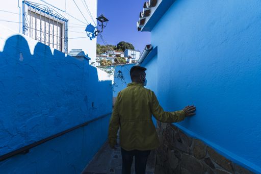 A male wearing a yellow jacket while standing in a narrow alley
