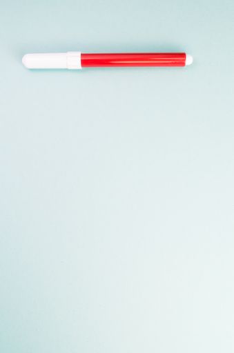 A vertical shot of a red marker on a light blue surface