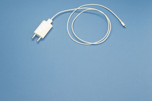 A high angle shot of a white smartphone charger on a blue surface