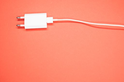 A top view of a white smartphone charger on a peach-colored surface