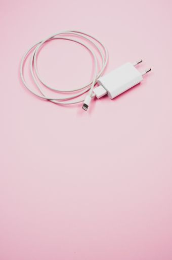 A vertical shot of a white smartphone charger on a pink surface