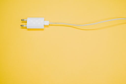 A top view of a white smartphone charger on a yellow surface