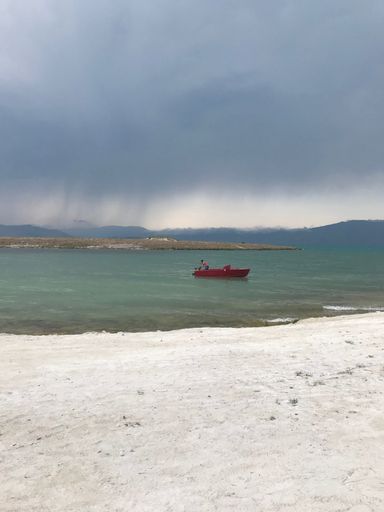 A vertical shot of a lonely person paddling in a red boat in the sea under the foggy sky