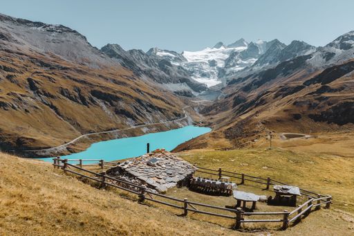 Swiss chalet in a meadow overlooking the turquoise Lake and Glacier of Moiry, in Val d'Anniviers, Valais, Switzerland