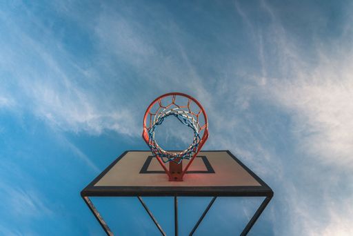 A low angle shot of a basketball hoop with blue sky in the background