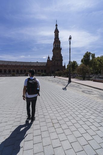A vertical shot of a male tourist with a backpack walking around the Plaza de Espana, Spain