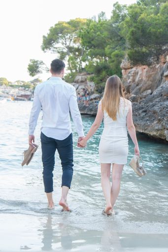 A vertical shot of a male and female couple romantically walking on the seashore while holding hands