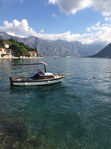 16 July 2019 - Kotor, Montenegro: Gorgeous view over the clear water of Kotor Bay on a sunny day with mountains in the background.