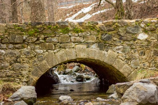 A closeup shot of a brick bridge over a river