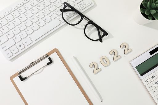 A flat lay shot of a computer keyboard, a calculator, a copybook and glasses - 2022 financial goals
