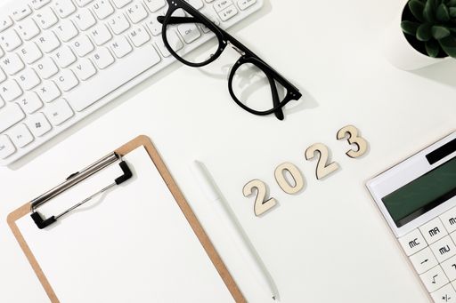 A flat lay shot of a computer keyboard, a calculator, a copybook and glasses - 2023 financial goals