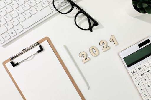 A flat lay shot of a computer keyboard, a calculator, a copybook and glasses - 2021 financial goals