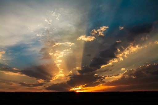 A silhouette of a field under a cloudy sky during a beautiful sunset - perfect for wallpapers
