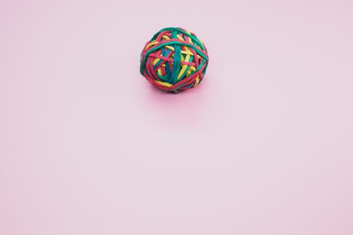 A top view of a rubber ball made out of rubber bands isolated on a pink background