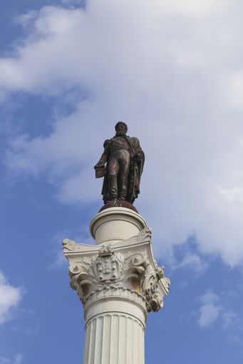 A vertical shot of the Column of Pedro IV monument in Lisbon, Portugal against a cloudy blue sky