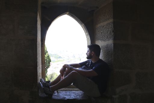 A handsome Caucasian man looking through an old castle window in Lisbon, Portugal