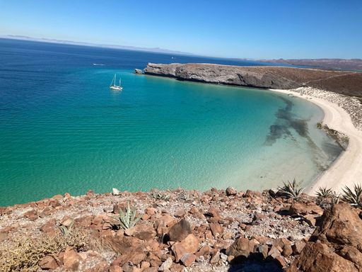 A scenic shot of Baja California against the sea with boats swimming around