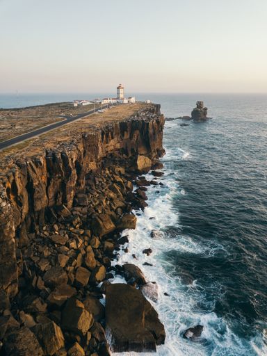 A vertical shot of a beautiful seaside view with the Cabo da Roca Lighthouse in the distance, in Peniche, Portugal