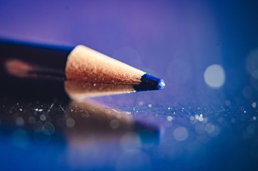 A closeup of a blue colored pencil on a reflective surface