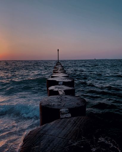 A majestic twilight view over wooden posts leading to a wavy sea