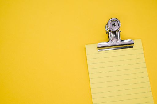 A top view of a notepad with a paper clipper isolated on a yellow background