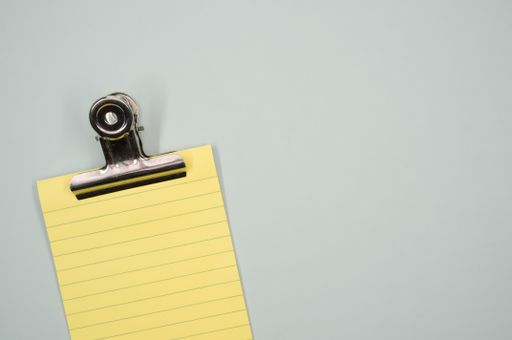A top view of a notepad with a paper clipper isolated on a gray background