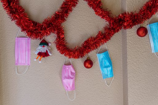 A closeup of a wall decorated with Christmas ornaments and facemasks - COVID-19