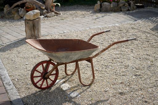 A closeup of an old rusty and weathered metallic wheelbarrow in the garden