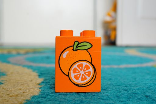 Orange Lego Duplo toy block with fruit illustration